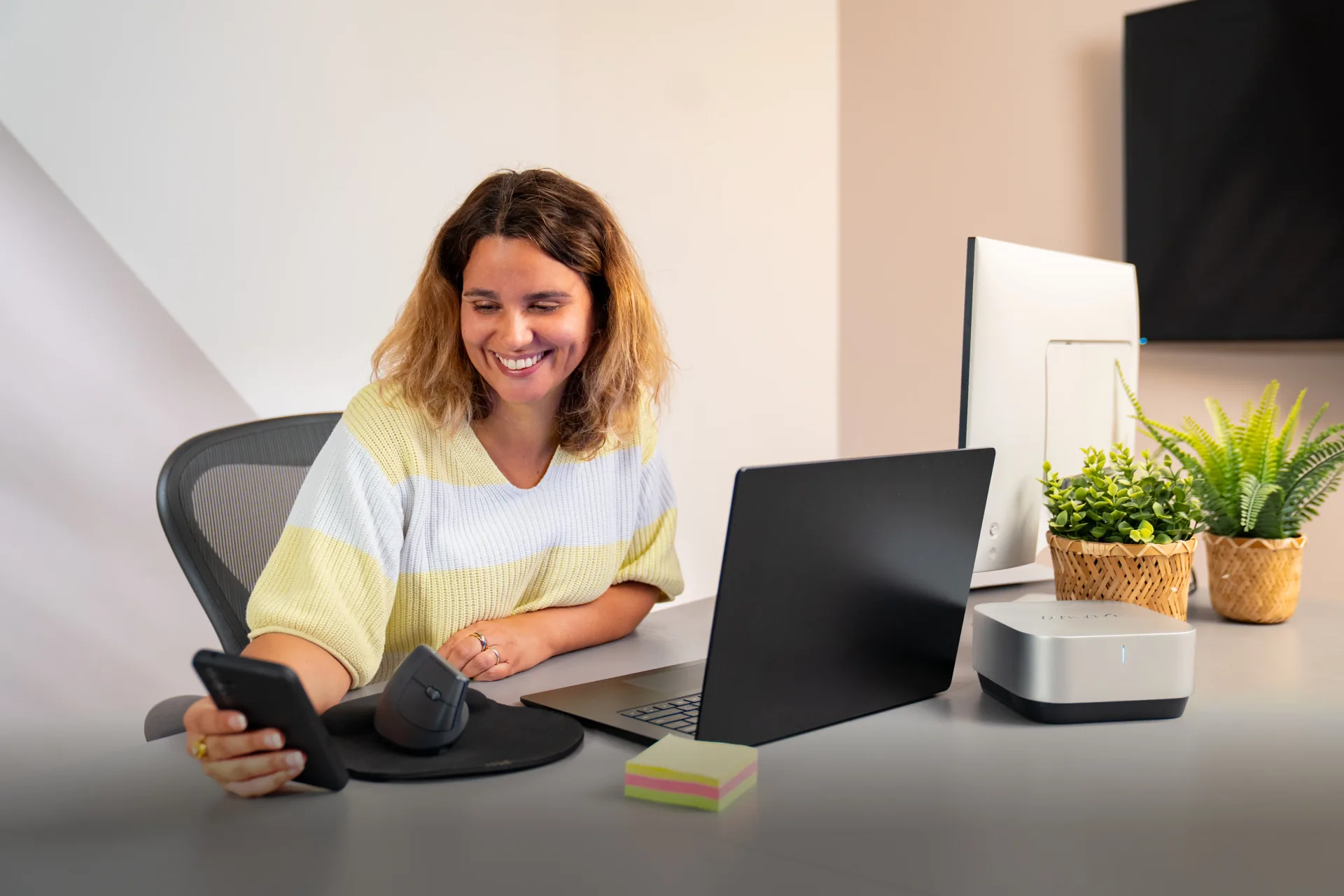 Smiling woman sitting at desk using Omna plug and play AI device next to laptop